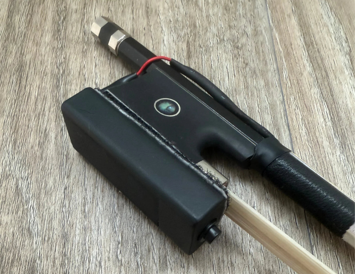 Black Bow with a cylindrical component on a wooden surface