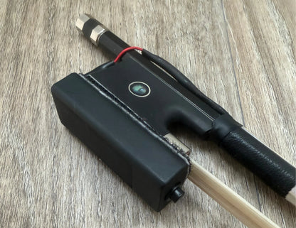 Black Bow with a cylindrical component on a wooden surface