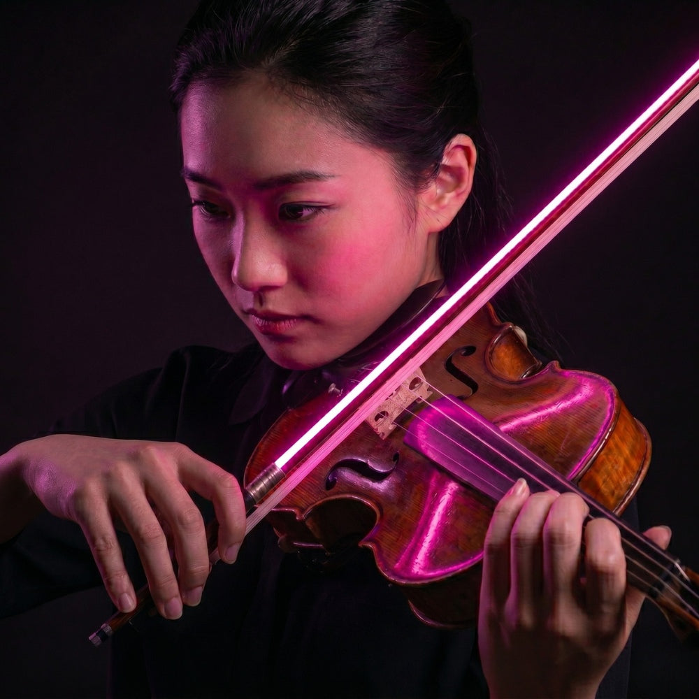 Women playing a violin with pink light effects in a dark setting